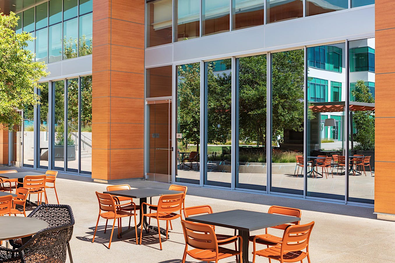 Outdoor seating area with closed sliding doors at a modern office building on a sunny day