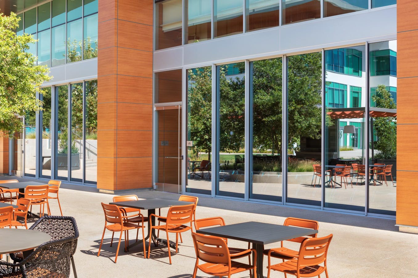 Outdoor seating area with closed sliding doors at a modern office building on a sunny day