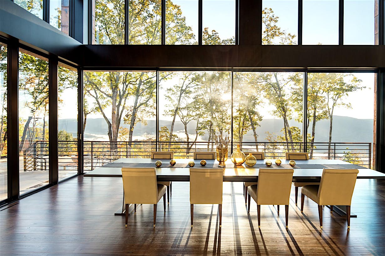 Contemporary dining room with panoramic glass doors opening to scenic mountain view.