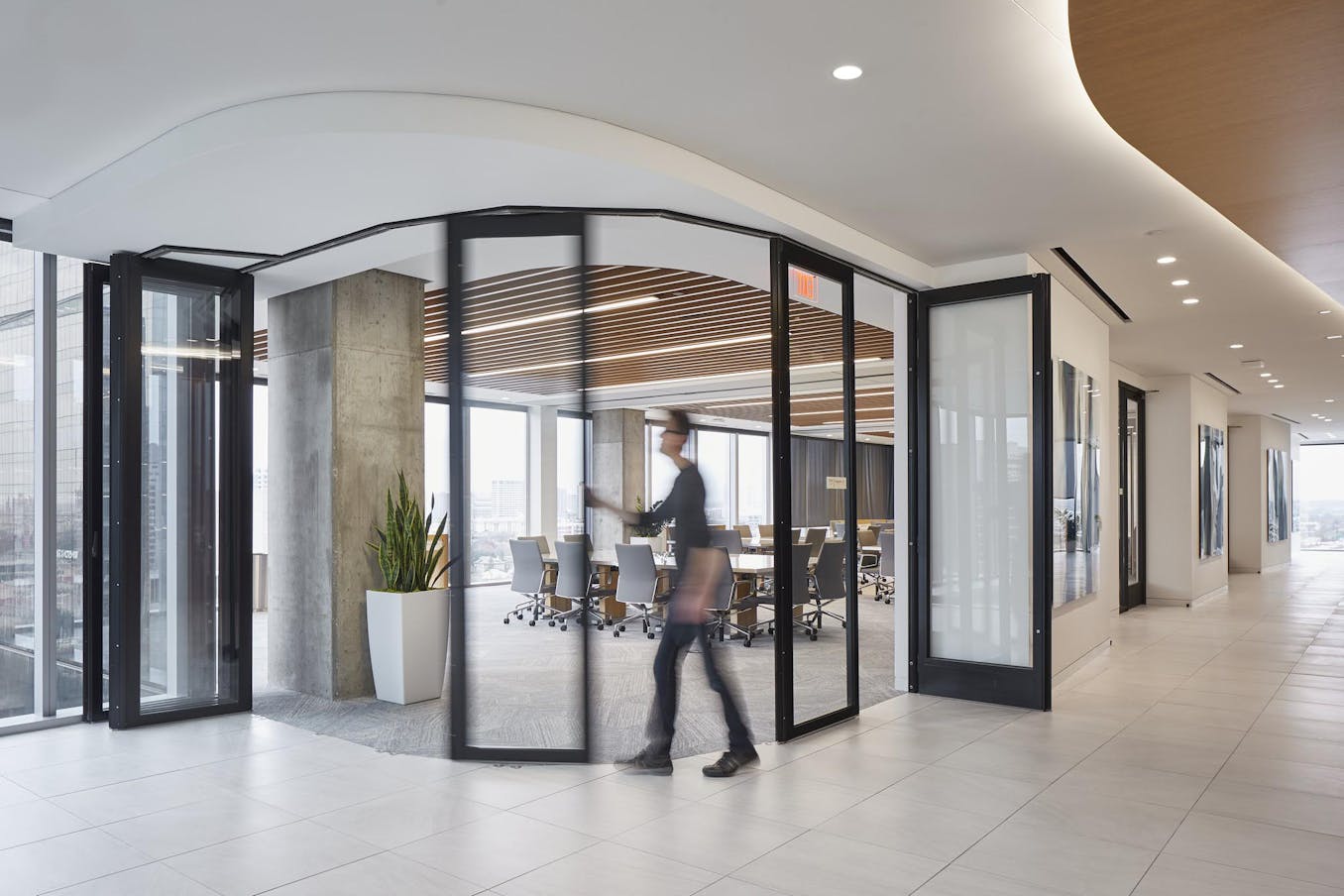 Commercial office space segmented curved sliding glass walls