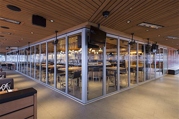 Modern restaurant with aluminum-framed glass wall partitions closed to create a flexible space by separating indoor and outdoor dining areas.
