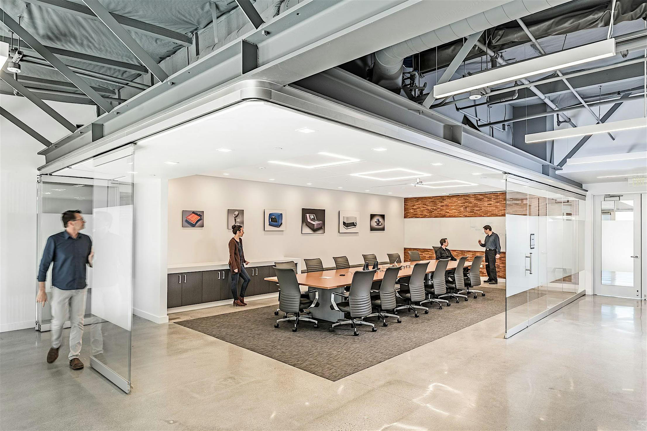 Modern conference room with glass walls, featuring a person sliding a smooth-operation glass door panel.