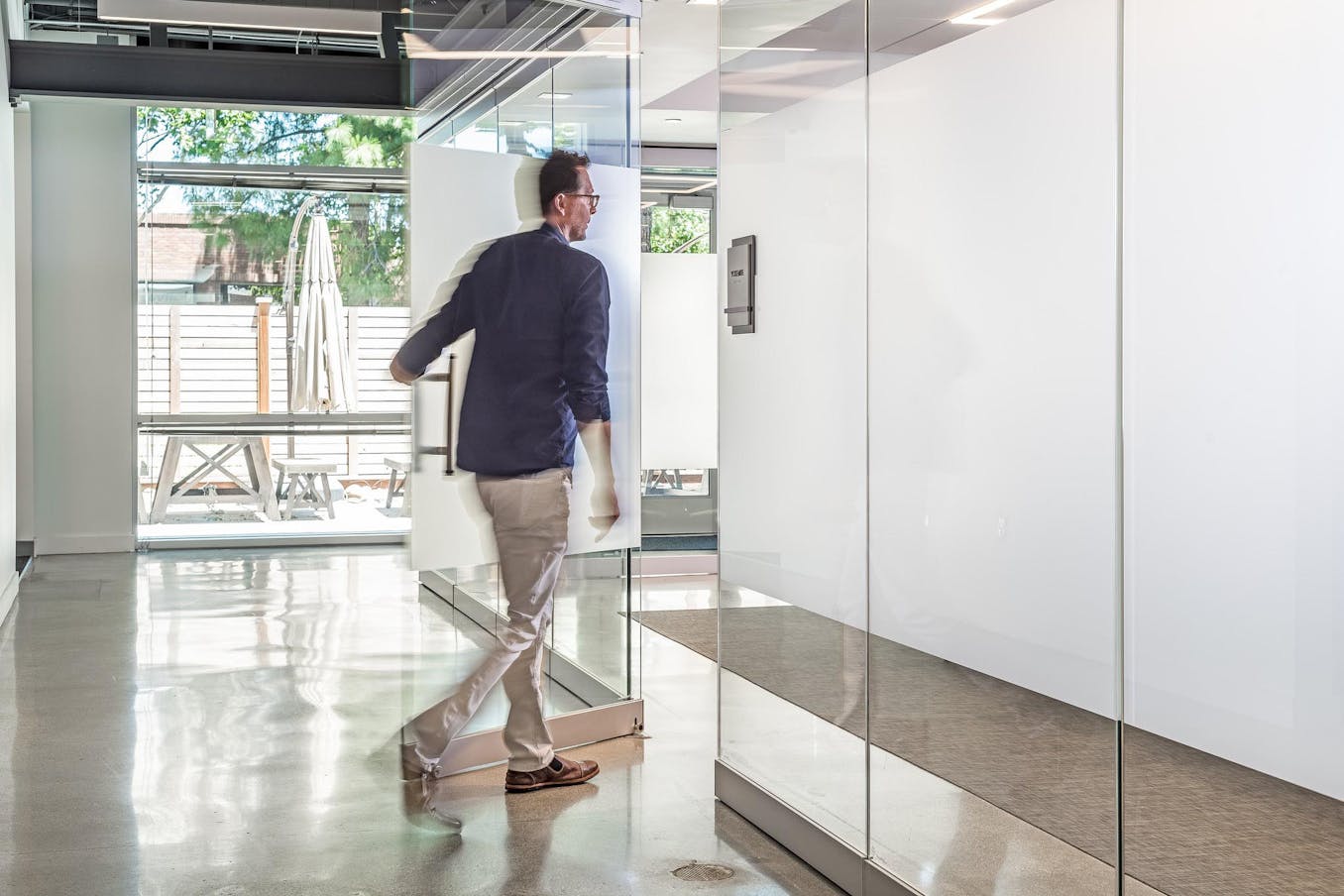 A man walking through a white glass door in an office