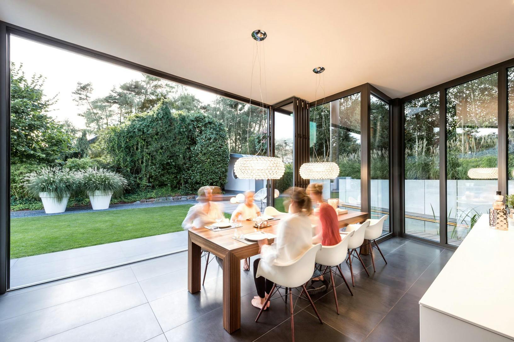 A group of people sitting around a dining table and opening patio folding doors