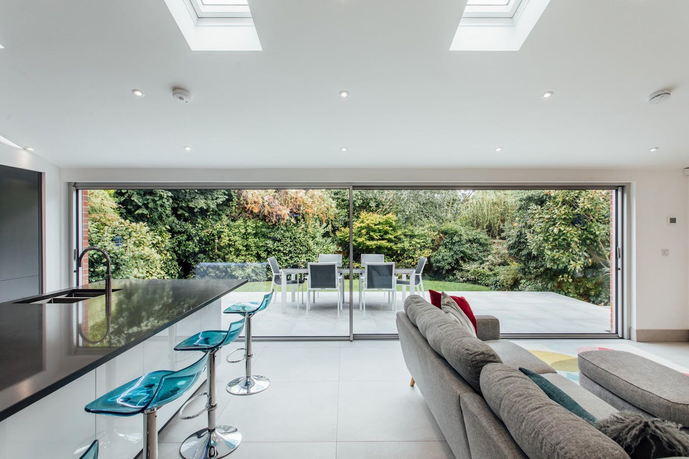 A modern kitchen and dining room with skylights and large opening glass walls