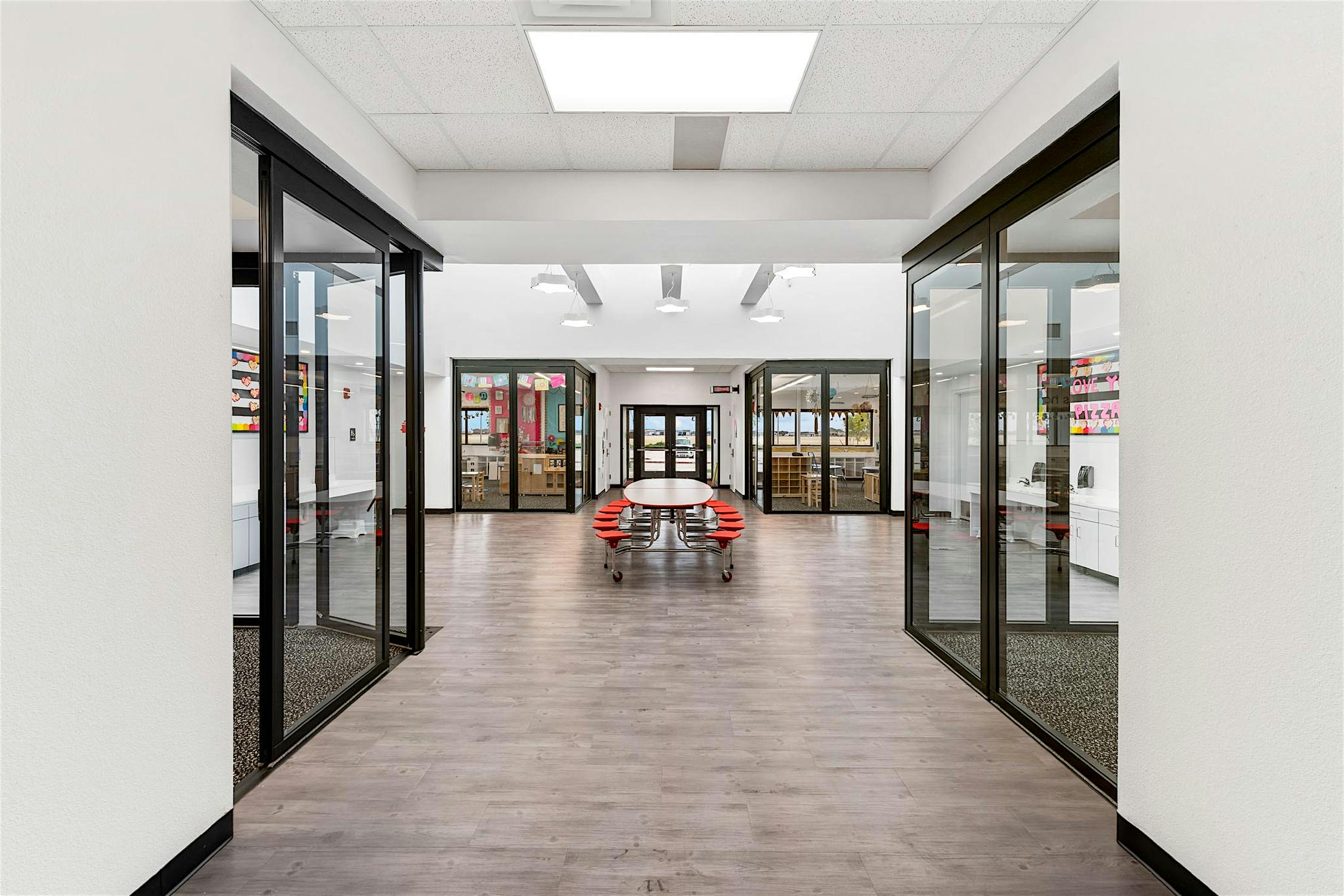 A hallway with folding glass doors on either side leads to seamless transitions between classrooms into the learning hubs