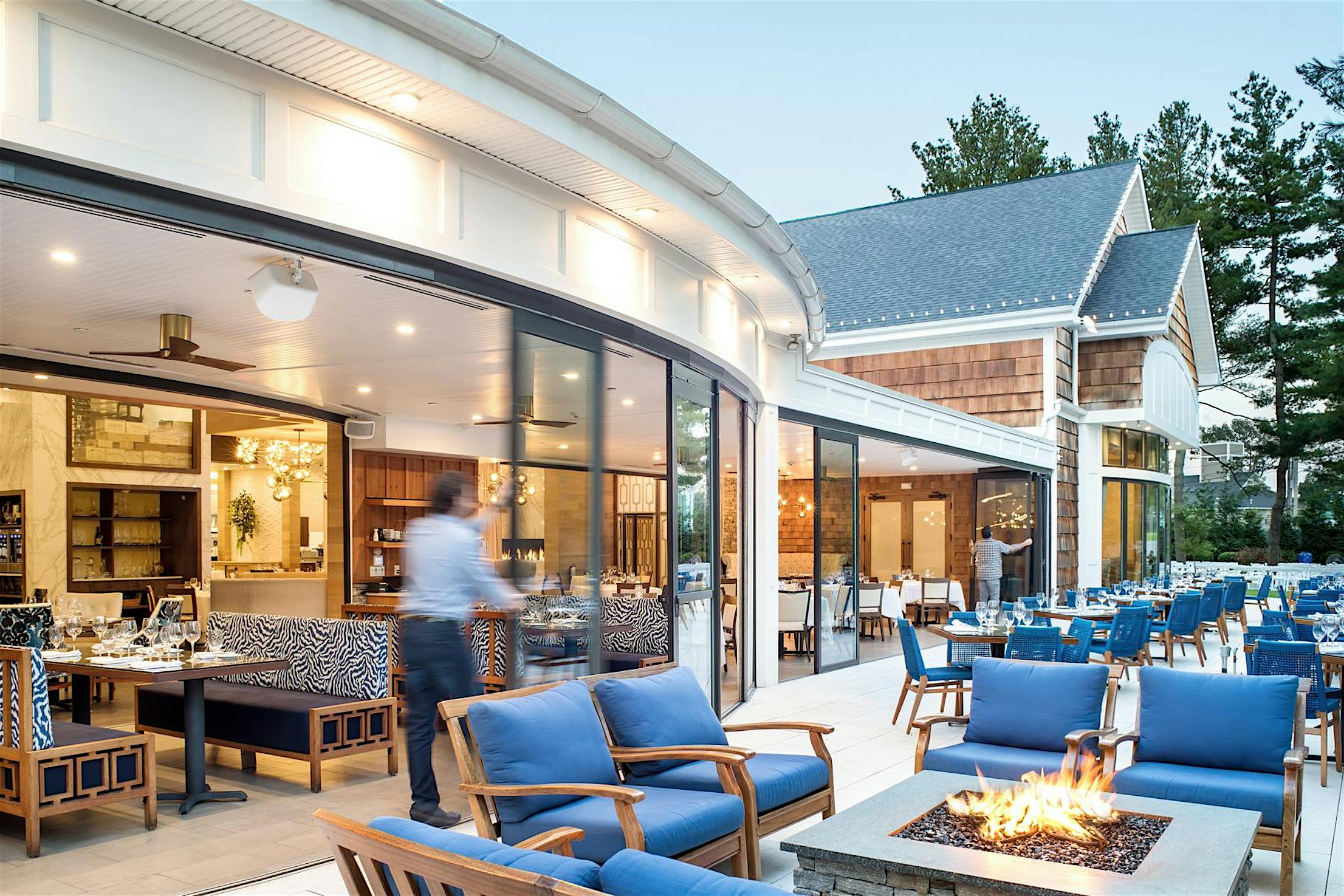 Open-air restaurant with indoor seating visible through large segmented curved sliding glass doors.