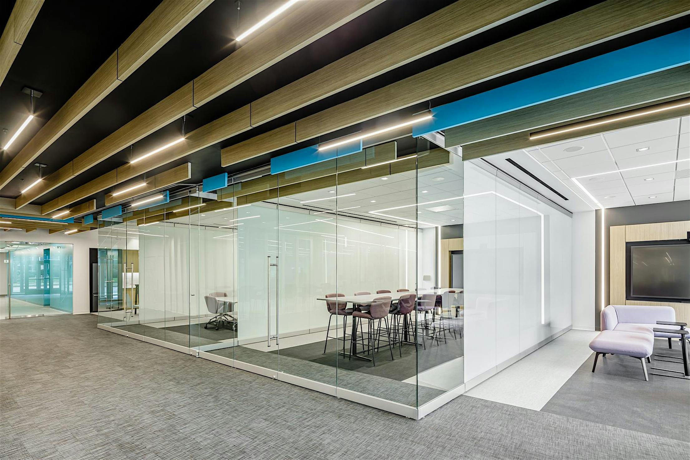 Modern glass-walled classroom with purple chairs and frameless glass partitions for flexible room configurations.