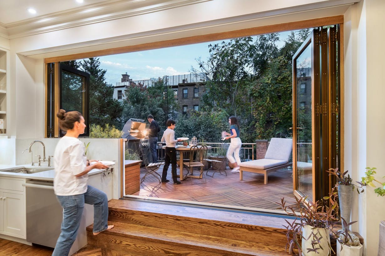 A kitchen with folding patio glass doors and a view of a garden