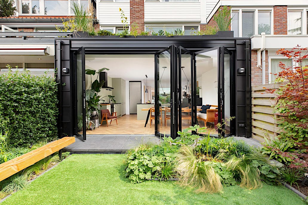 Bifold glass patio doors enhance the modern style of this Amstelveen townhouse, blending indoor and outdoor spaces