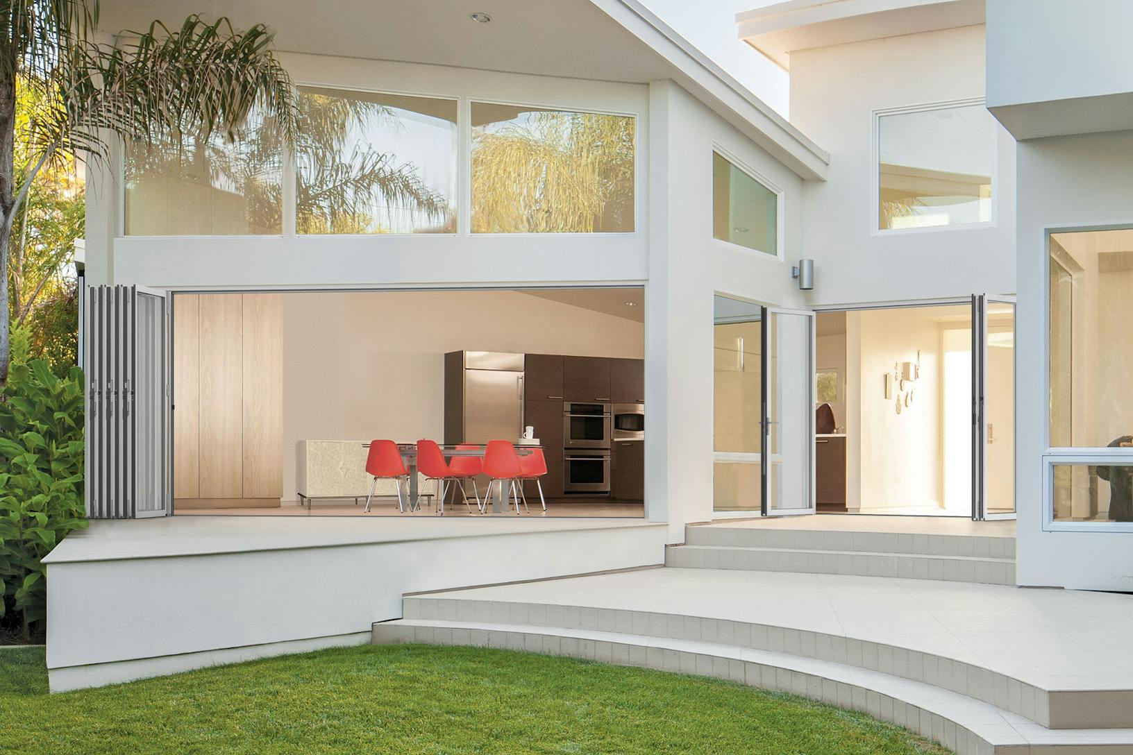 A white house with a patio and a table and chairs - Exterior folding patio doors
