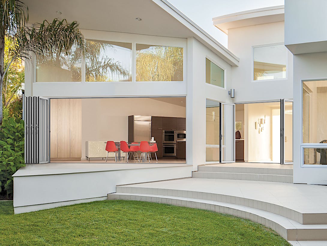A white house with a patio and a table and chairs - Exterior folding patio doors