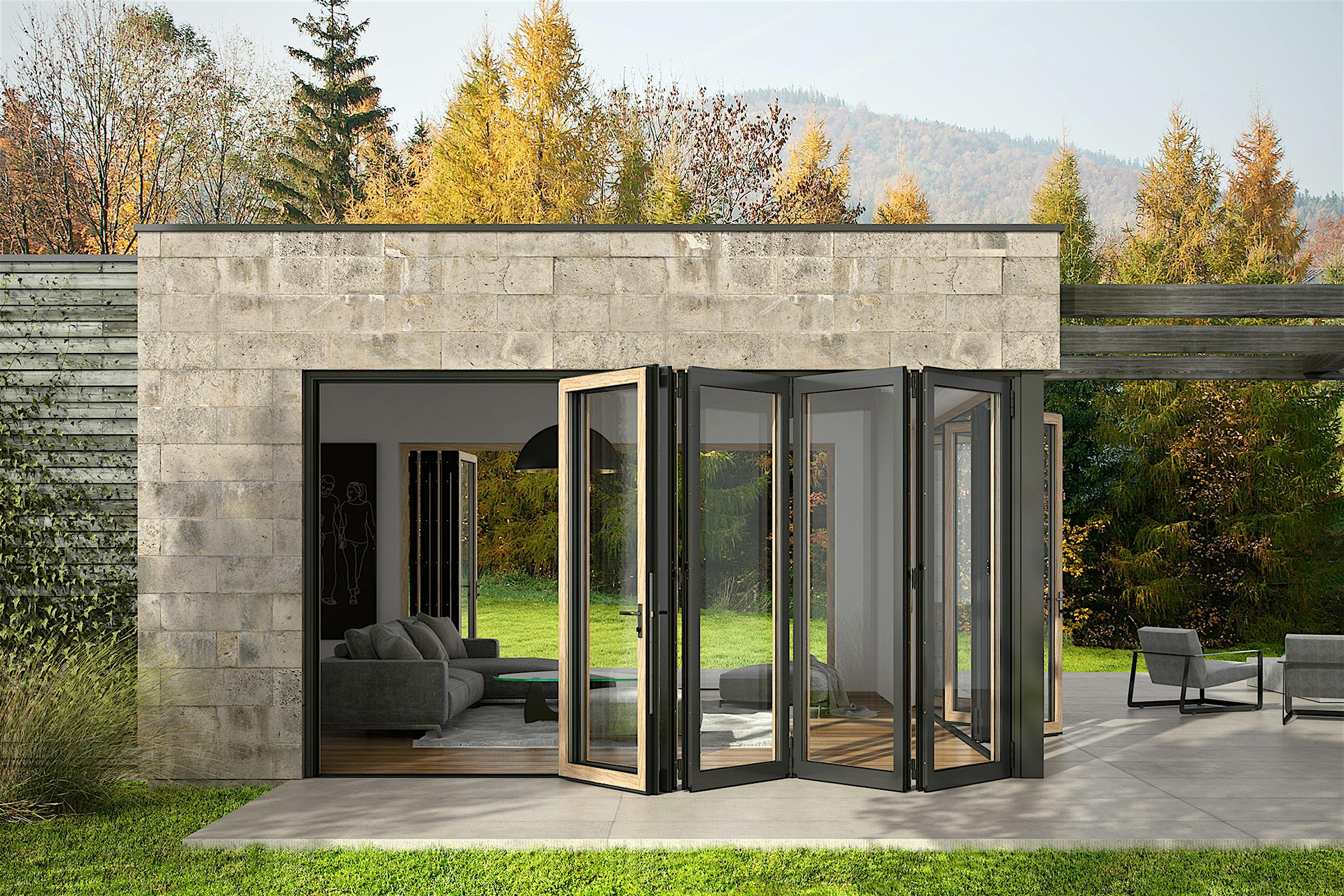 A modern ADU with open aluminum clad bifold glass doors leading from a living room to a patio, surrounded by trees and outdoor seating.
