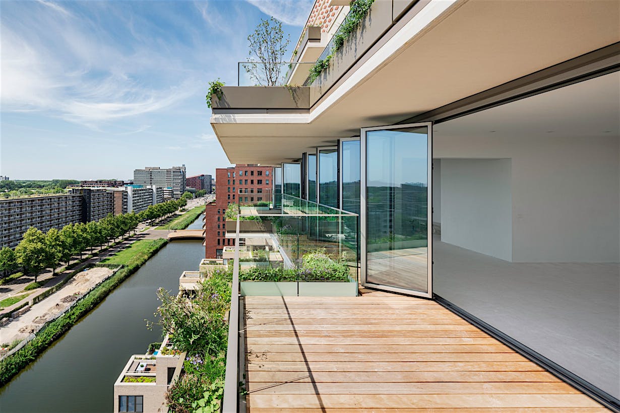 Modern apartment with aluminum accordion glass doors and large balcony overlooking the canal.