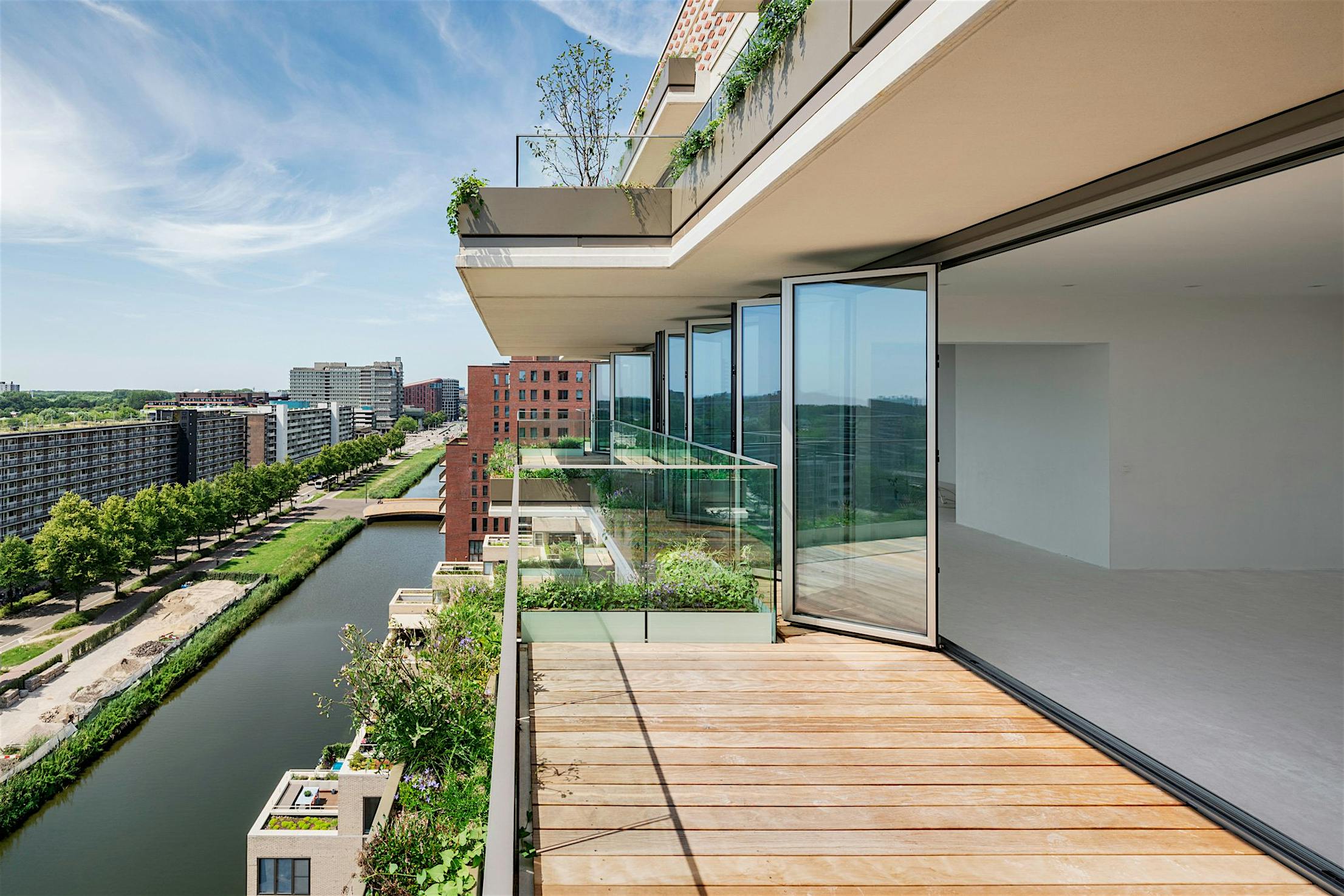Modern apartment with aluminum accordion glass doors and large balcony overlooking the canal.
