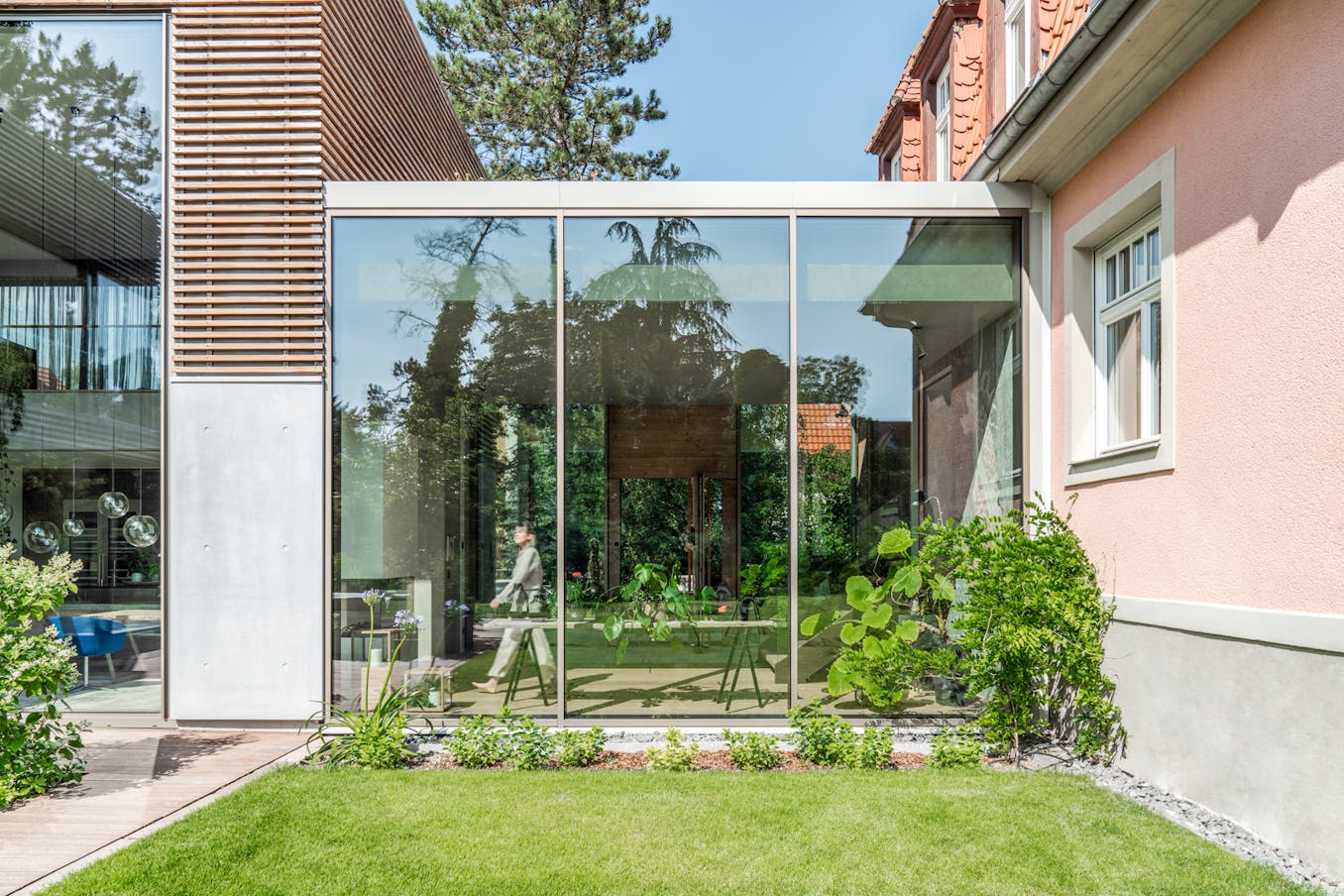 Modern house with large opening glass walls and a green lawn