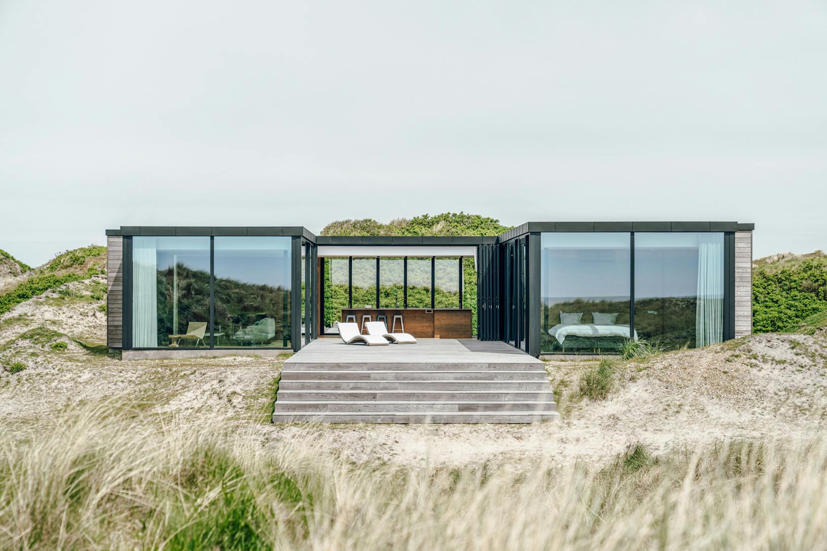 House in the dunes facing the ocean with floor to ceiling glass walls