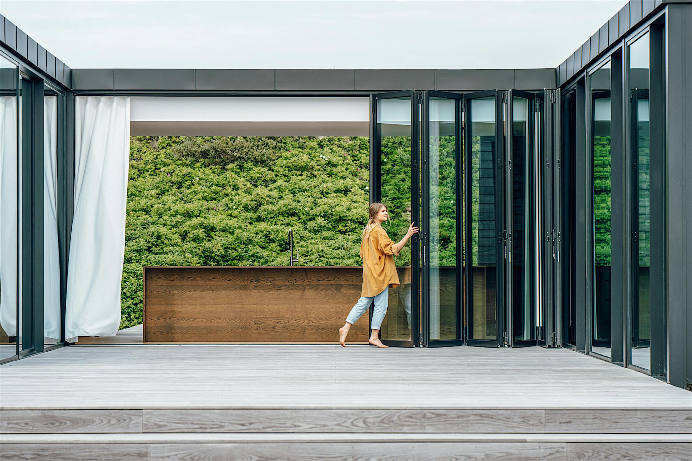 A woman enjoying the easy operation of a folding glass wall as she stands in front of glass doors