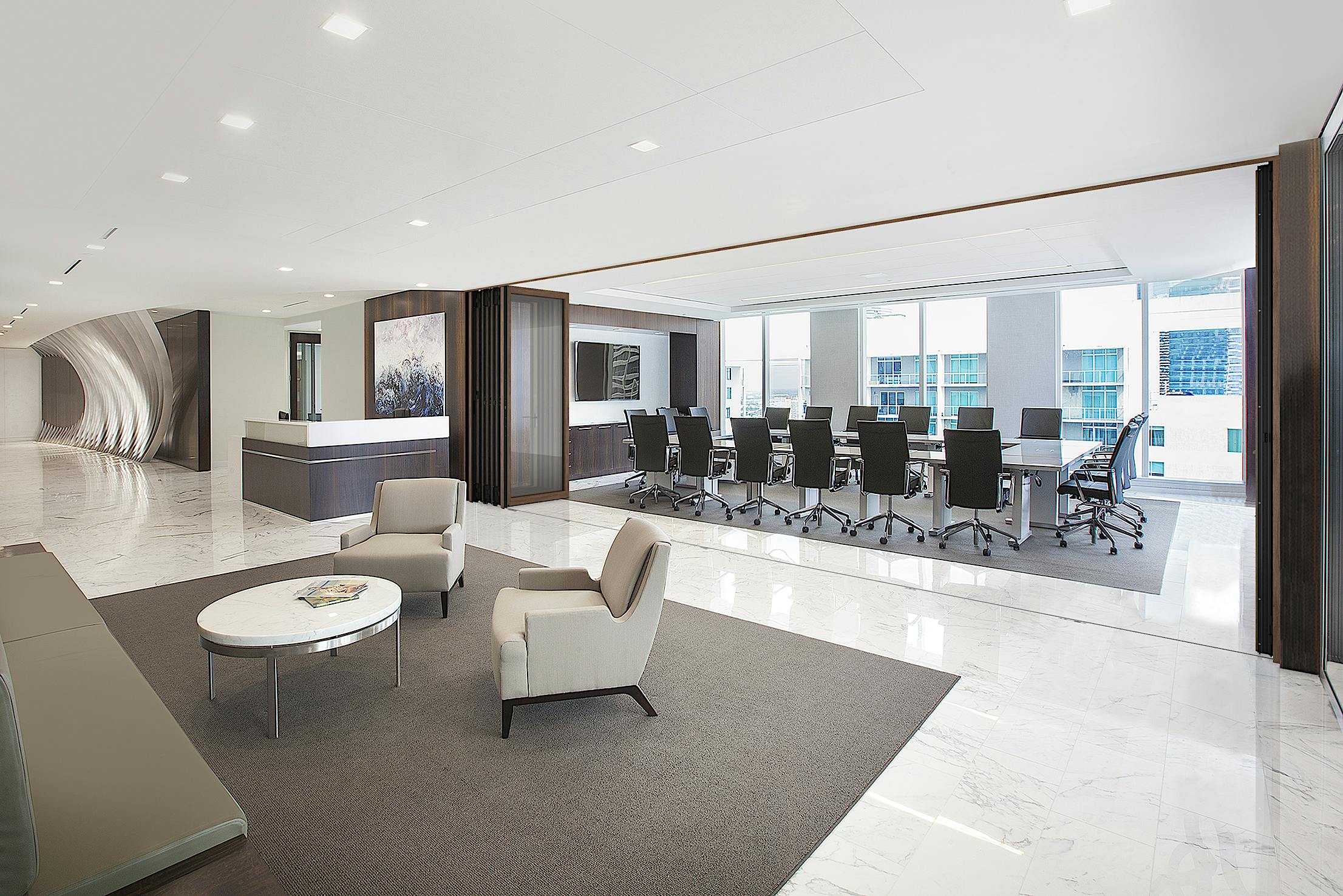 Modern office space with a reception desk, lounge area with chairs and a table, and a large glass-walled conference room.