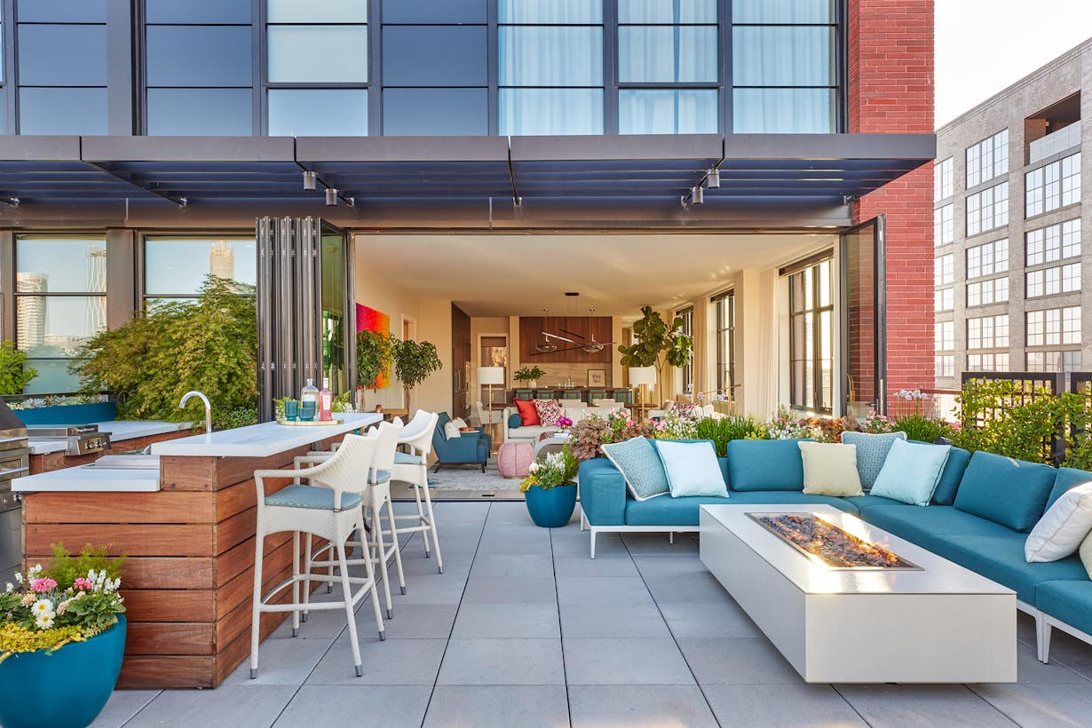 A rooftop patio with outdoor furniture and folding glass walls