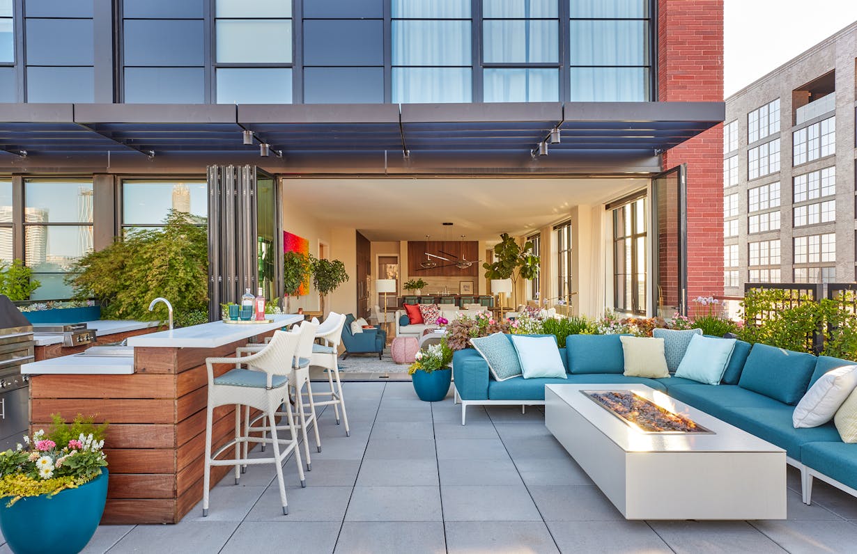 A rooftop patio with outdoor furniture and folding glass walls