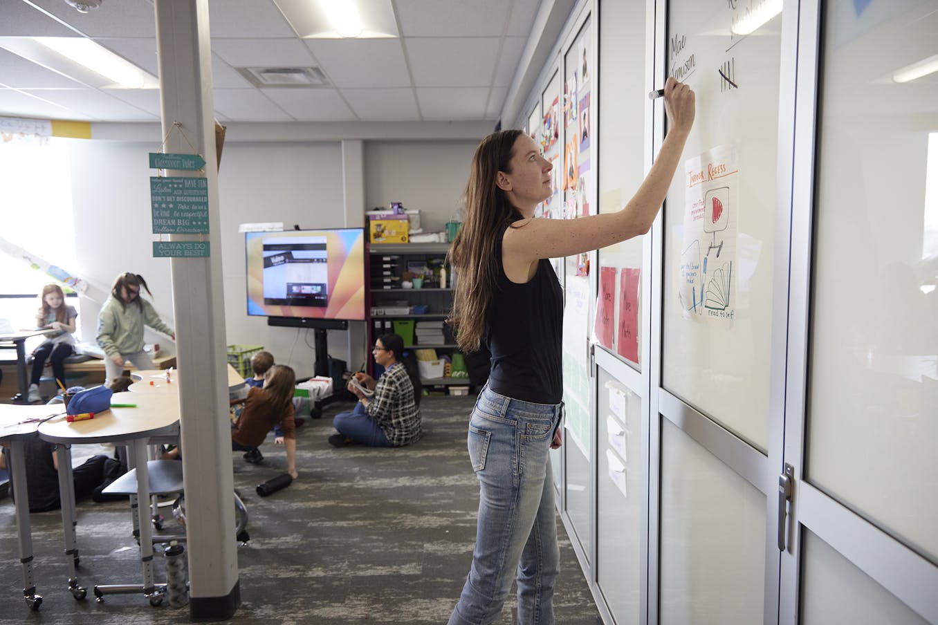 Teacher in a classroom using the white glass walls as a whiteboard