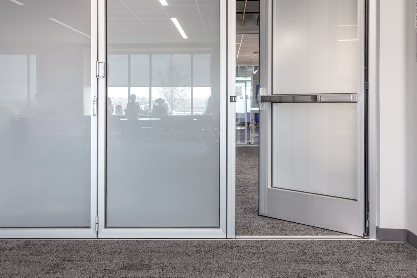 A classroom featuring frosted glass doors and swing door