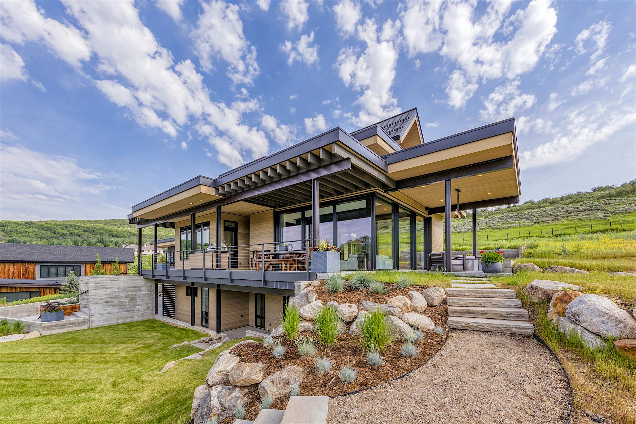 A modern home on a hillside with large panel minimal sliding glass walls overlooking the surrounding landscape