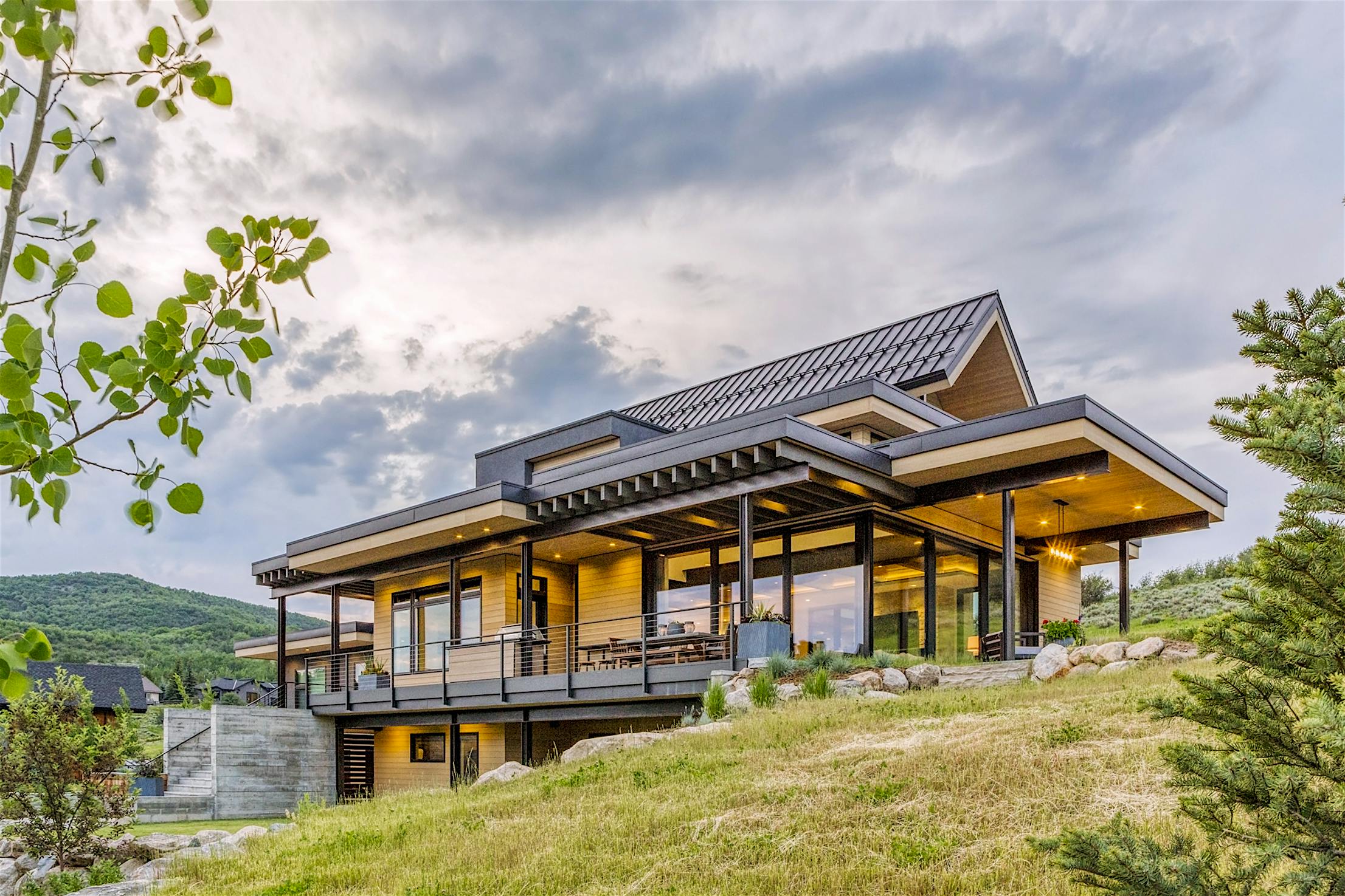 A modern home on a hillside with large panel minimal sliding glass walls