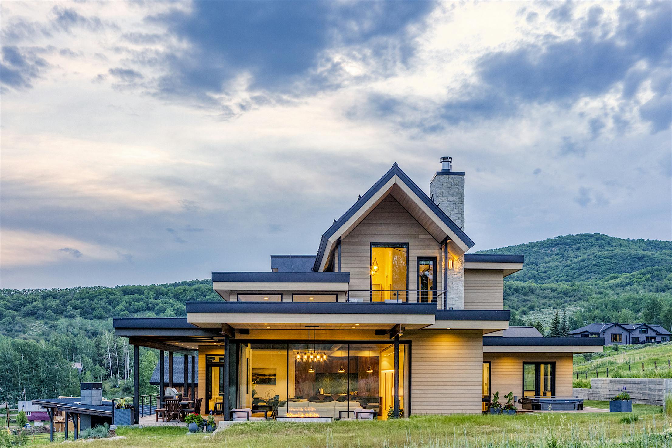 A modern home on a hillside with large panel minimal sliding glass walls overlooking the surrounding landscape