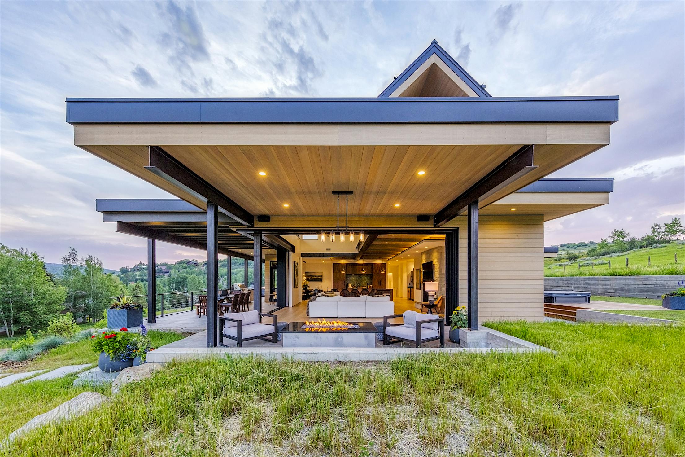 A modern home on a hillside with an opened minimal sliding glass walls