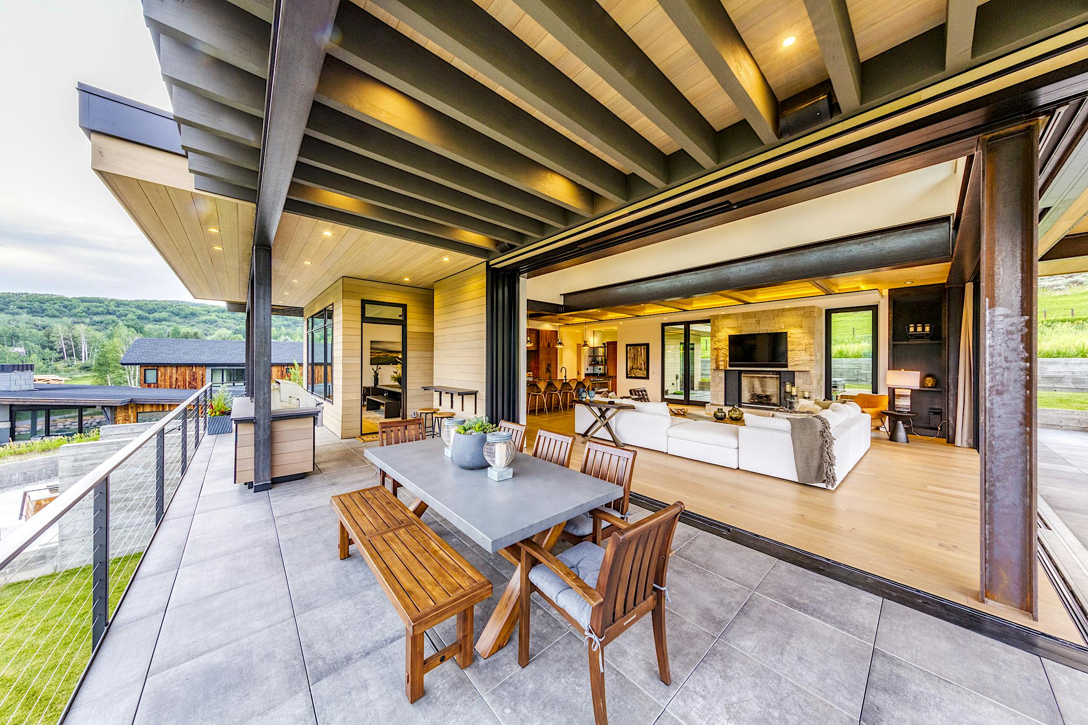 A modern home with a large panel sliding deck doors and outdoor furniture
