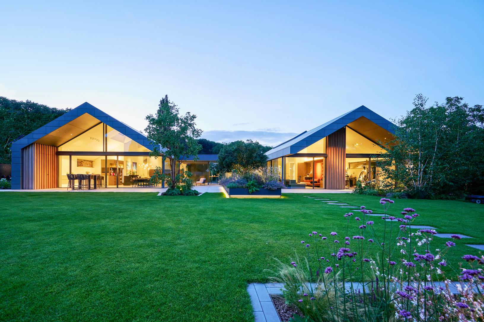 A modern house in the middle of a lush green lawn - exterior glass walls