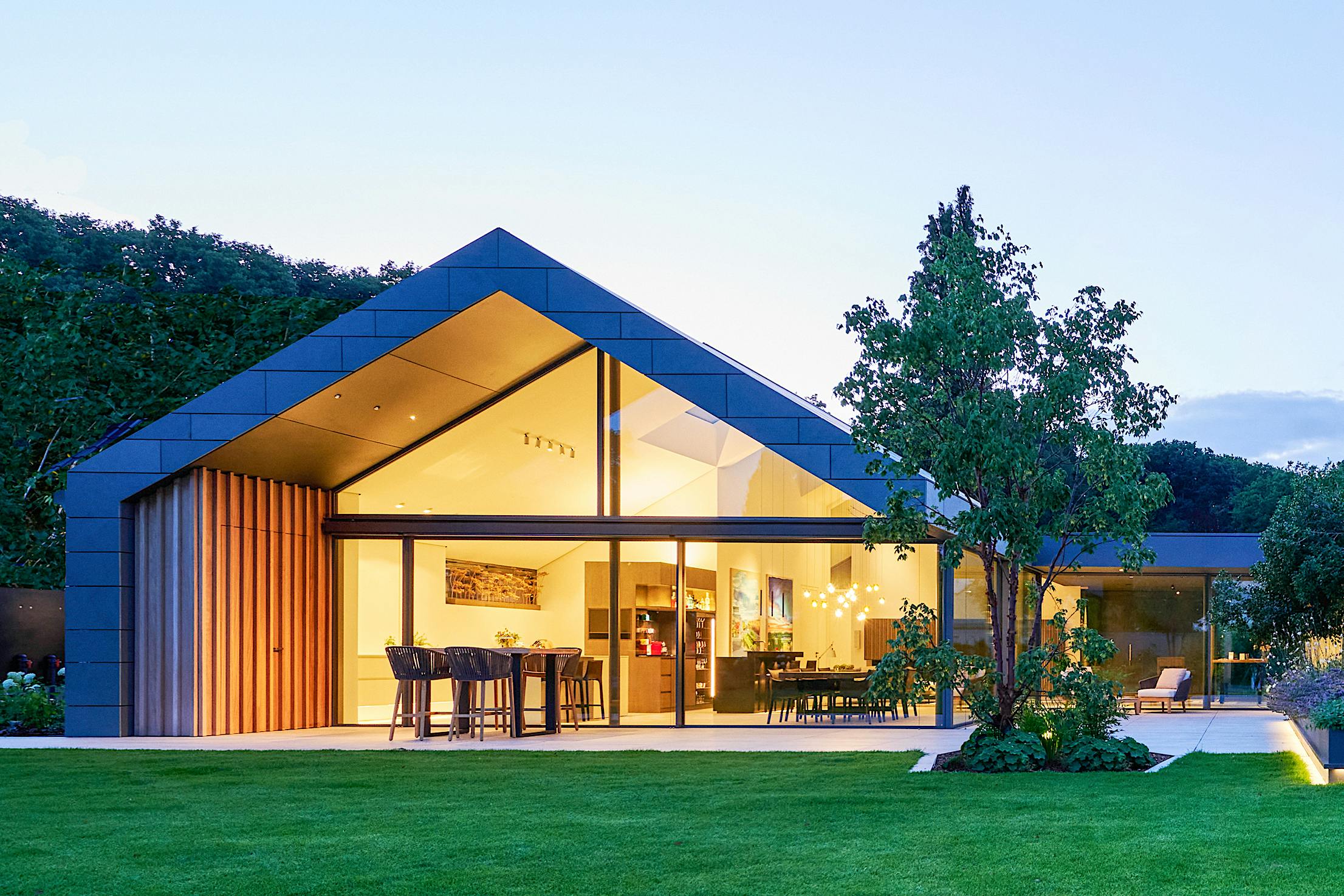 A modern house in the middle of a green lawn - Exterior large opening glass walls