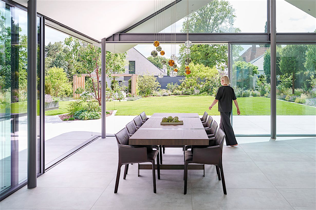 A modern dining room with glass walls and a wooden table