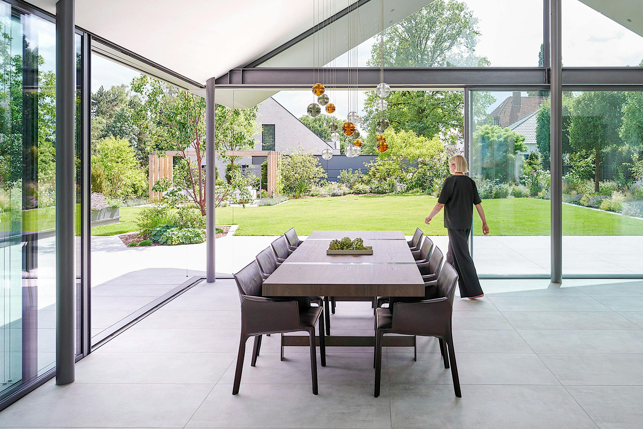 A modern dining room with glass walls and a wooden table