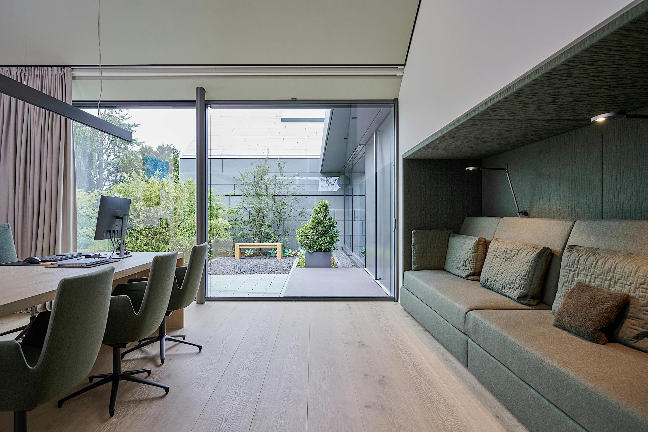 A modern office with a green couch and large opening sliding glass doors