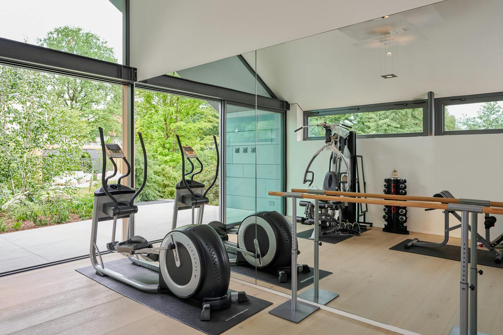 A gym room with exercise equipment and a large glass wall