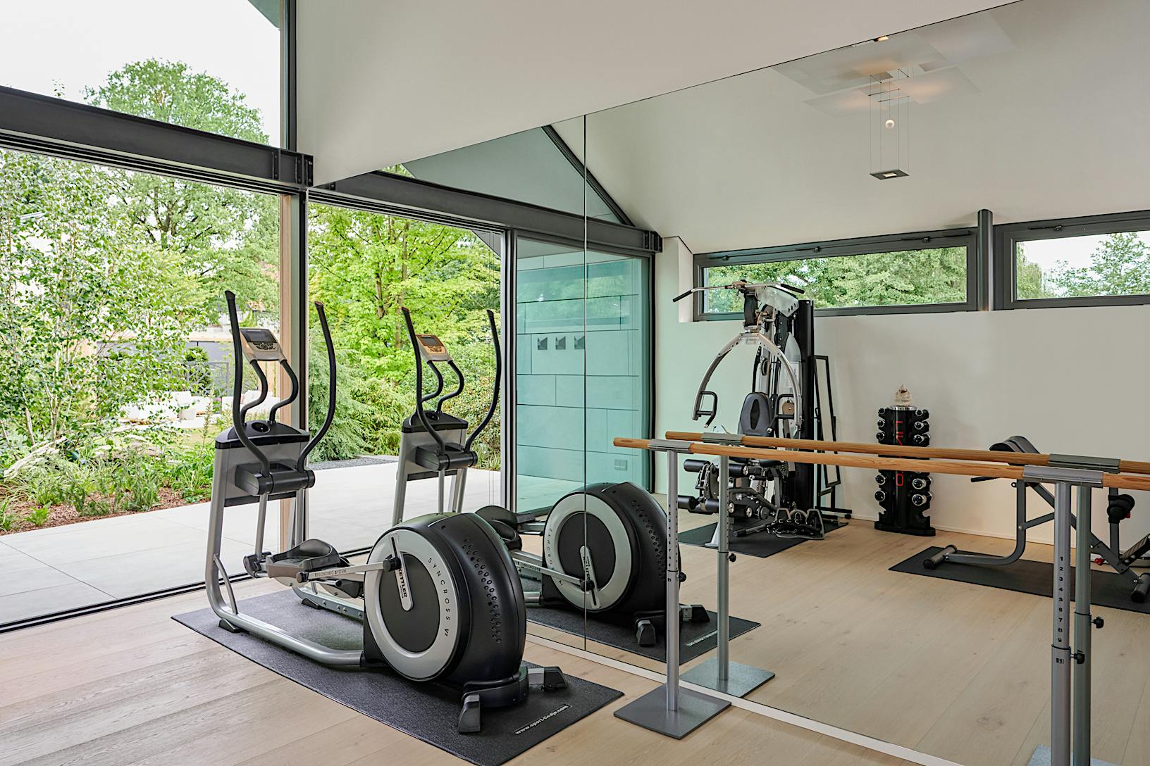 A gym room with exercise equipment and a large glass wall