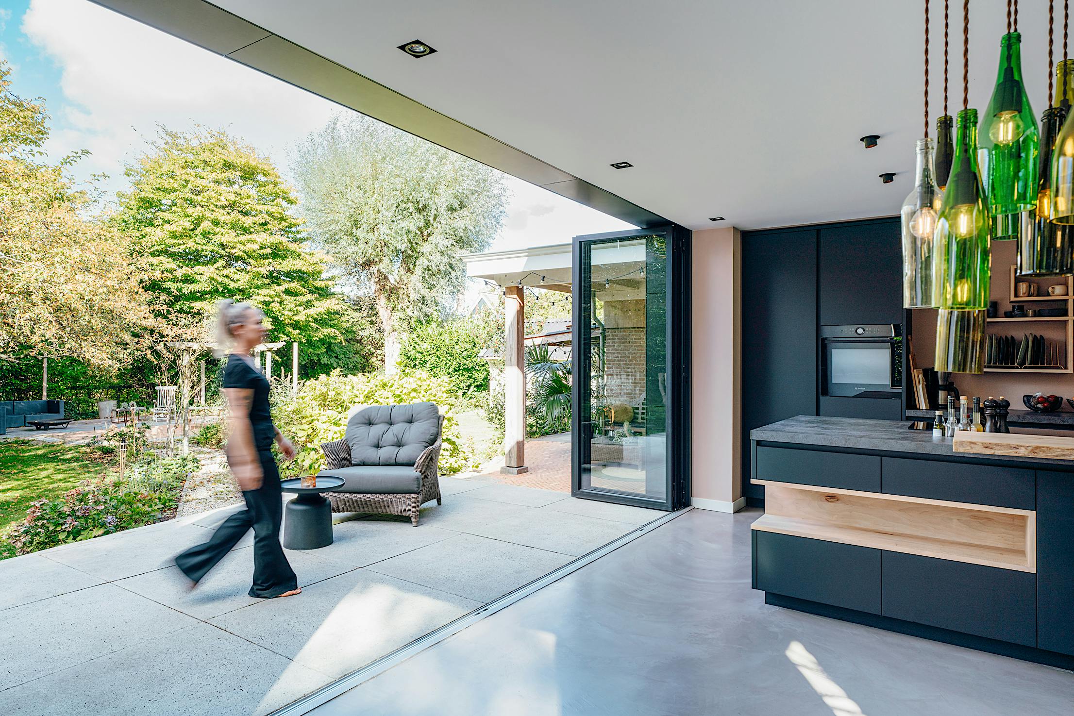 woman walks past a modern kitchen with folding glass doors