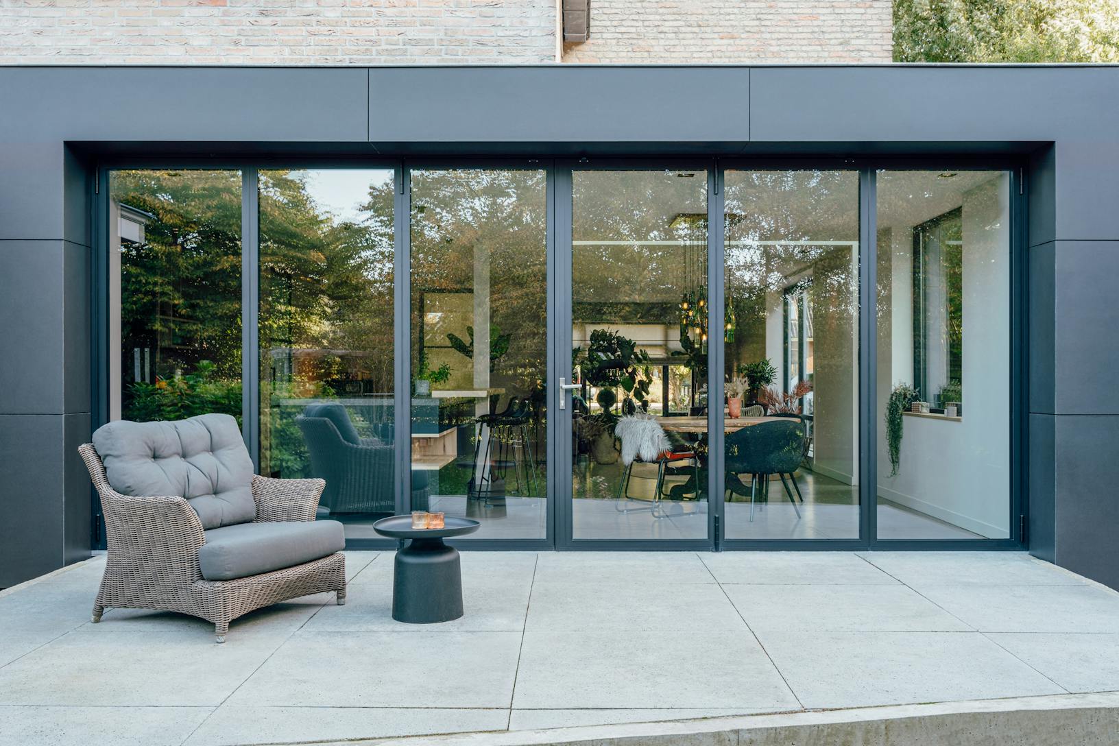 A modern patio with a black chair and table - closed exterior folding doors