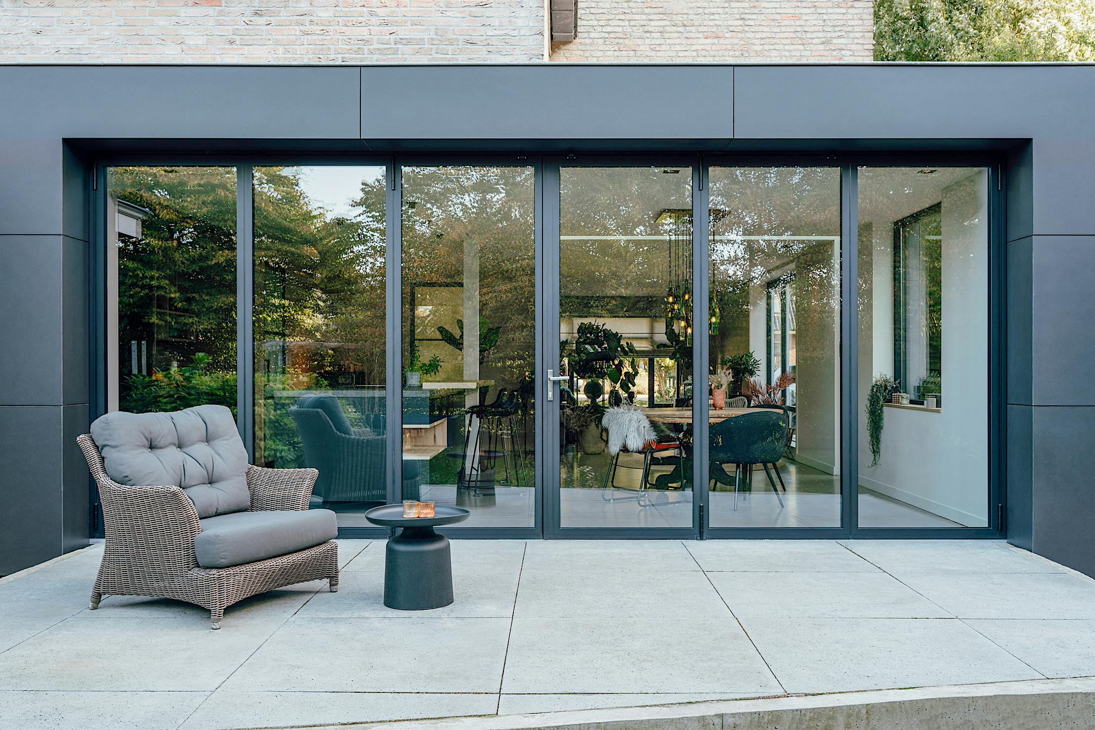 A modern patio with a black chair and table - closed exterior folding doors