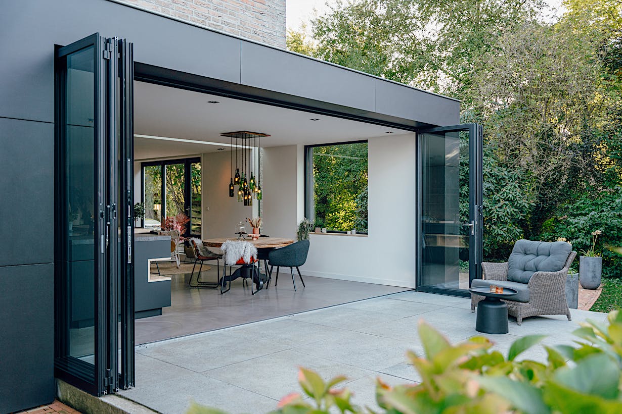 A modern patio with a black chair and table - open exterior folding doors