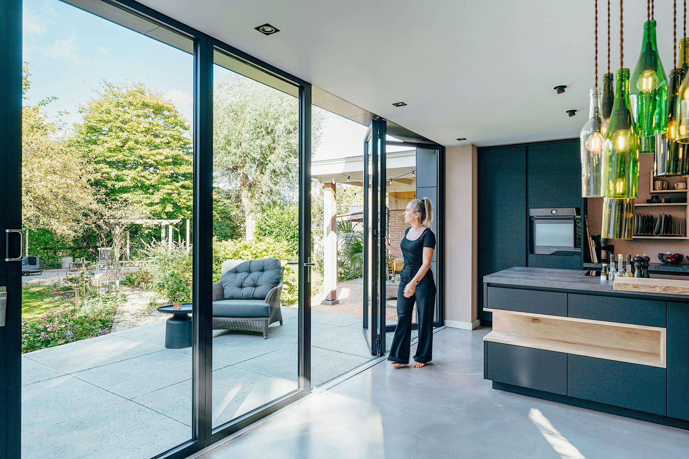 A woman standing in front of folding glass doors in a modern kitchen