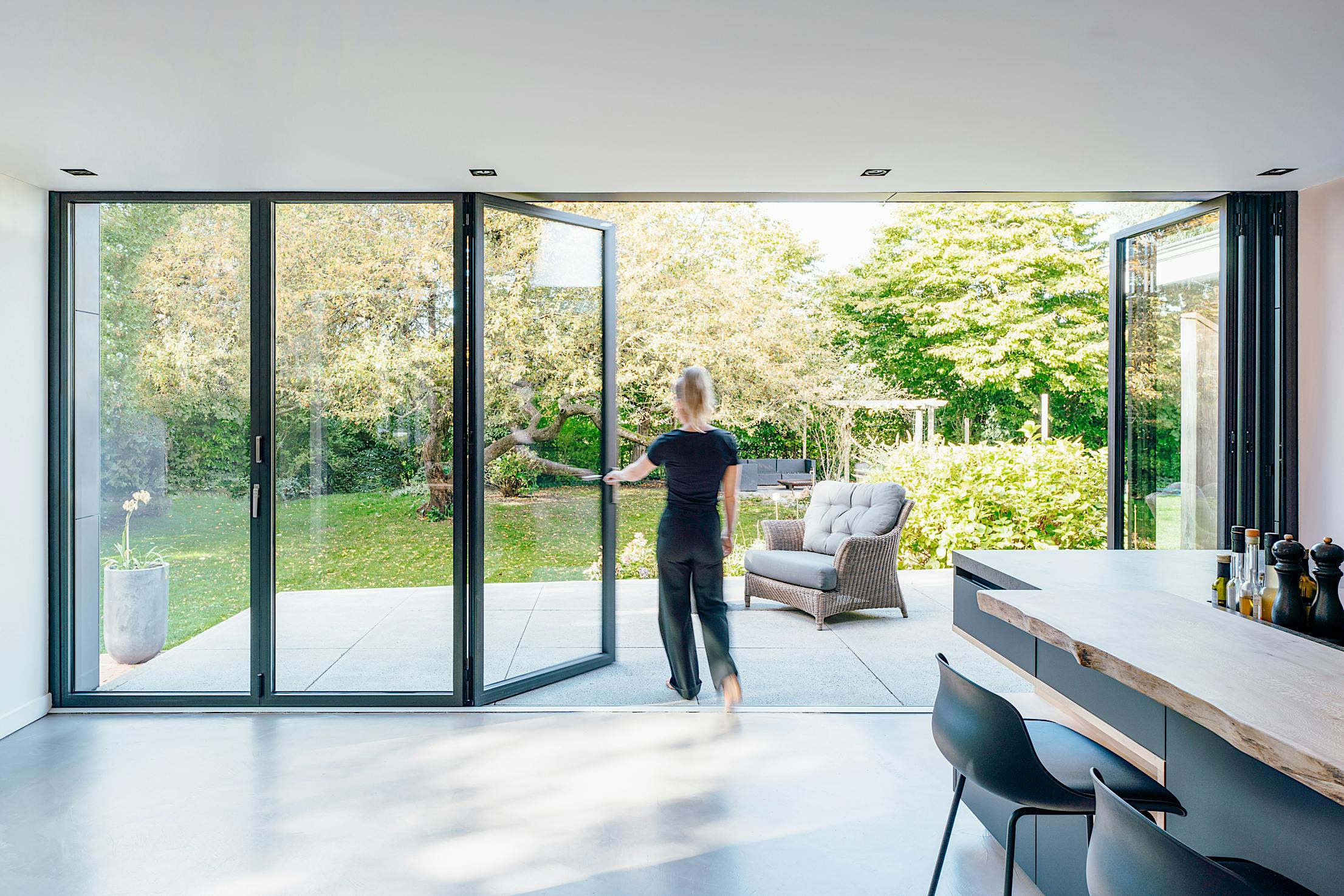 Retractable patio doors enhance a modern residence by seamlessly extending indoor space to the outdoors with clean aesthetics