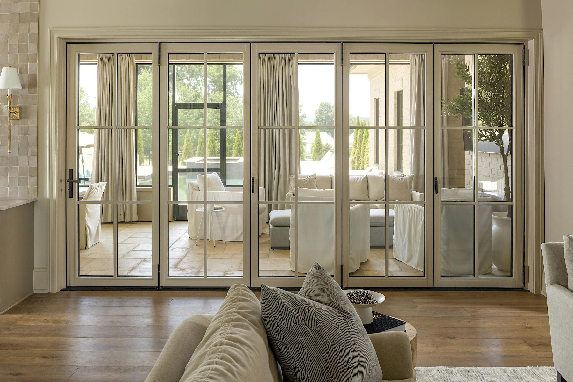 A living room with folding glass doors that seamlessly connect it to the dining room and kitchen