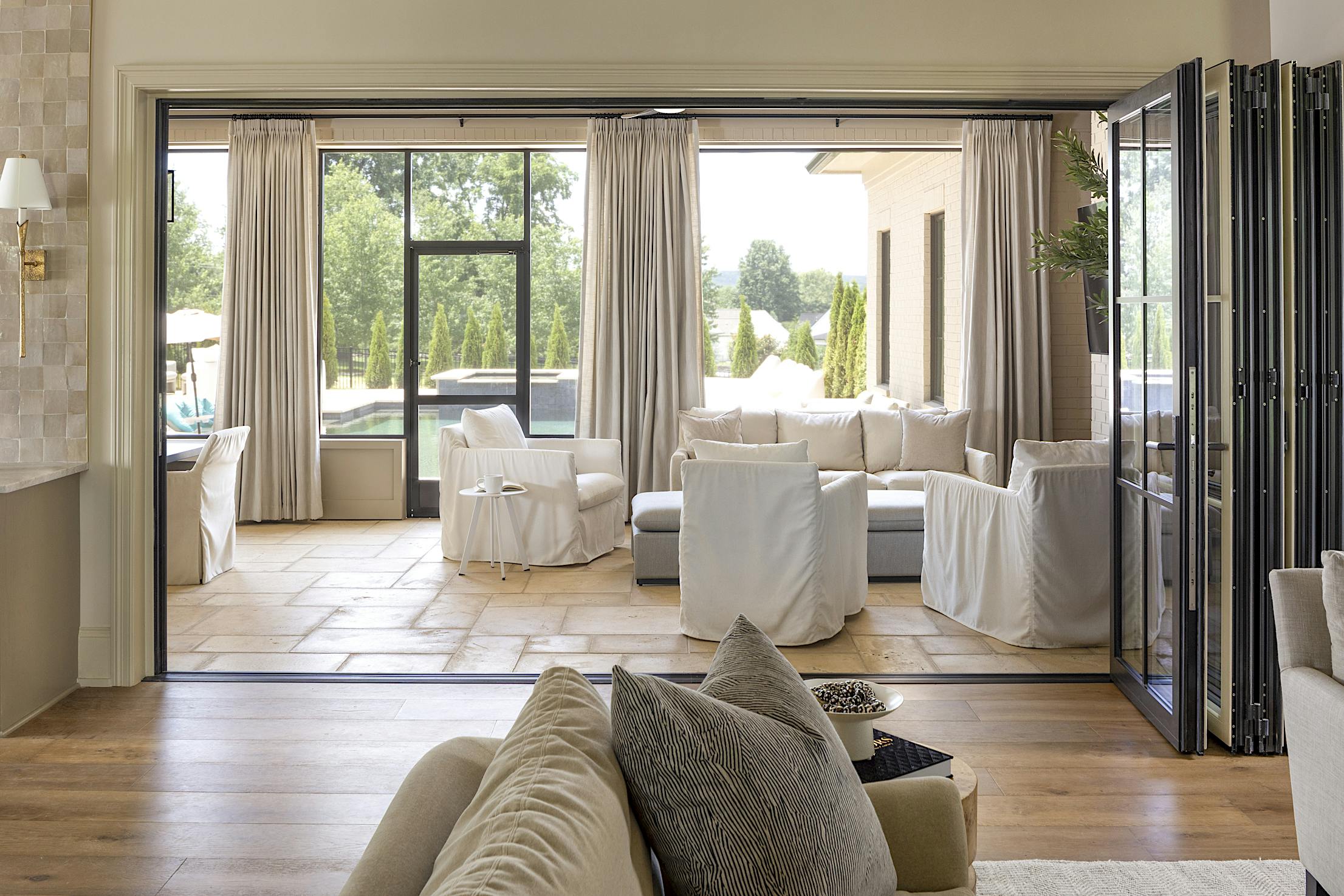 A living room with a folding glass door, offering a seamless connection to the dining room and kitchen