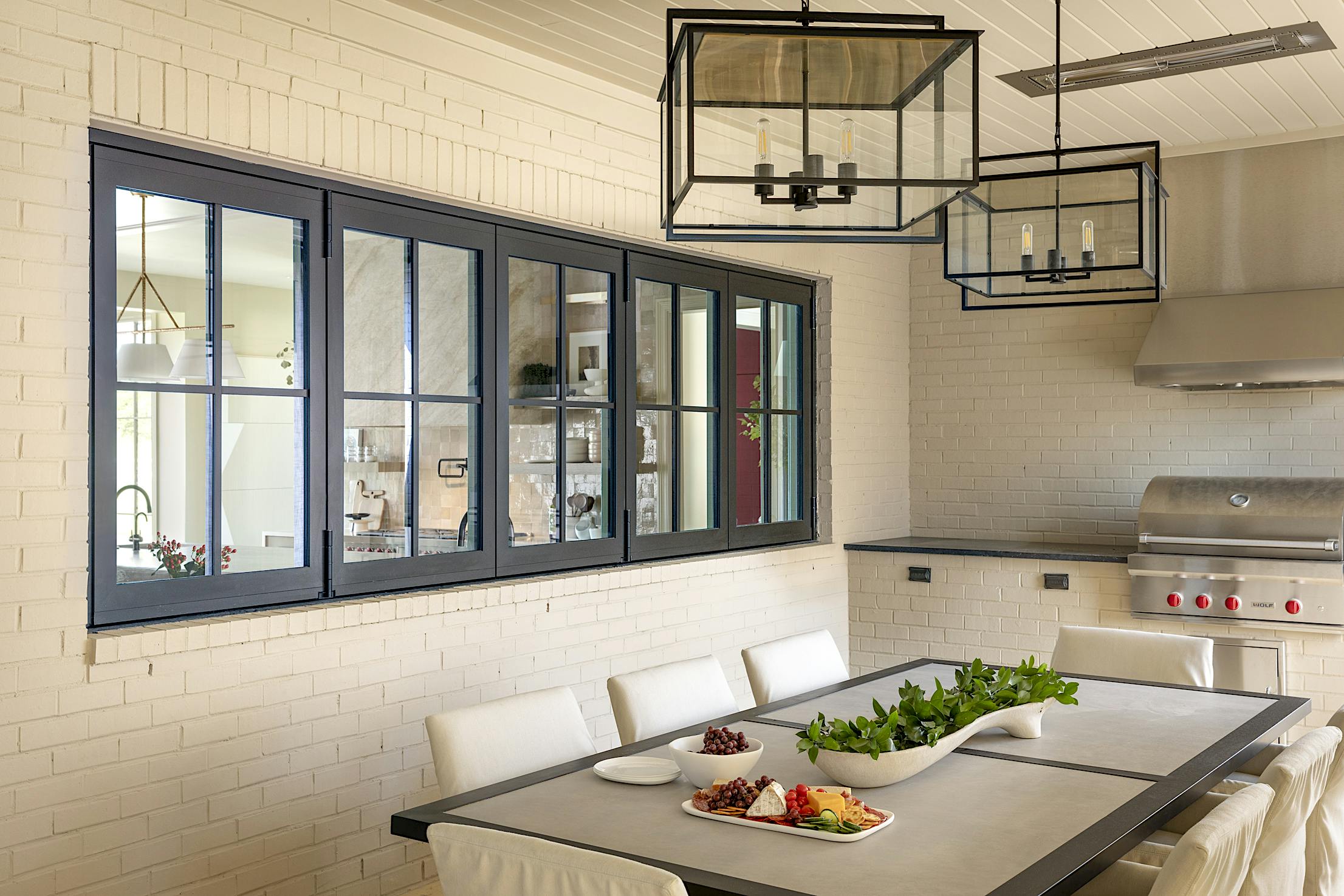 A dining room with a table and chairs, featuring kitchen windows
