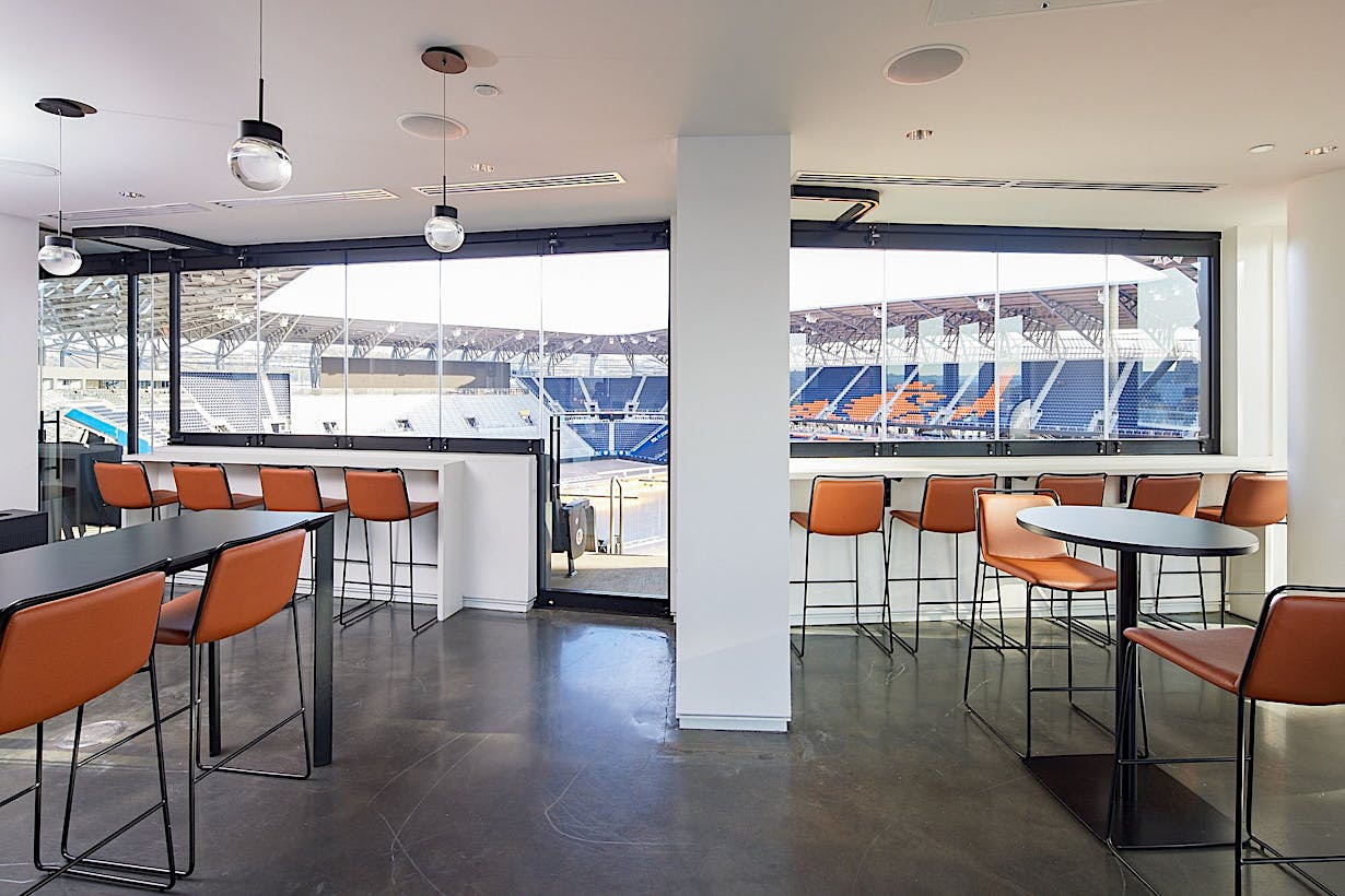 Suite with a bar with orange stools and A bar with orange stools and a Single Track Sliding view of a stadium