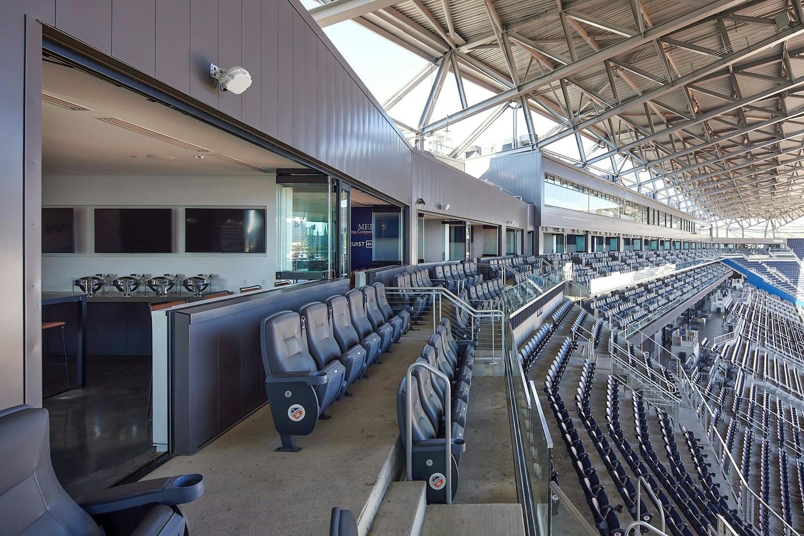 The inside of the TQL stadium with rows of seats - frameless glass panels